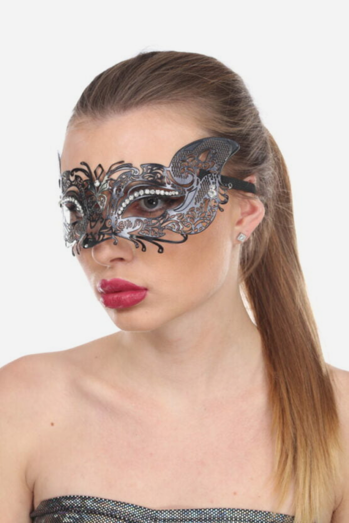 Model wearing the black metal fox masquerade mask over her eyes, its filigree ears and rhinestone trim framing her face, with a long ponytail and red lips.