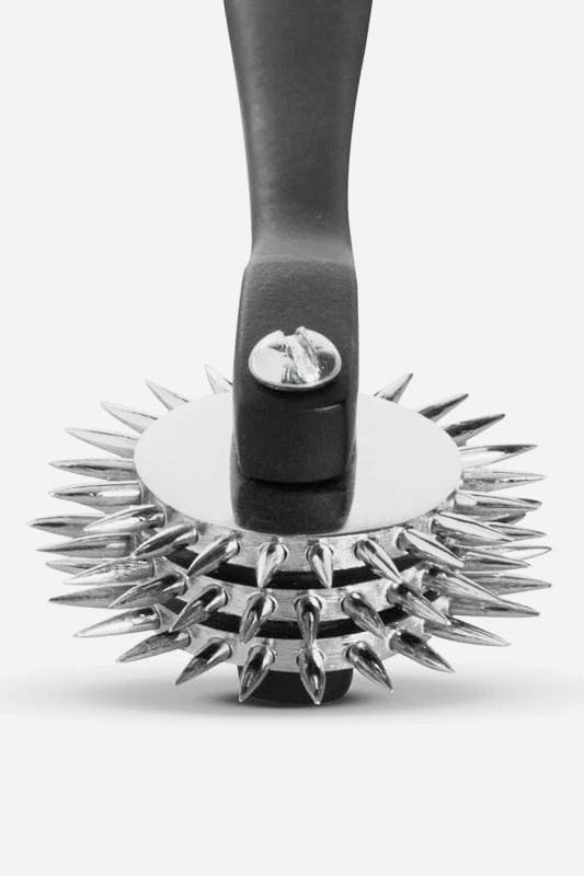 Close-up of a three-row spiked sensation pinwheel head with a dark grey handle, showing the stacked silver spike wheels from the front