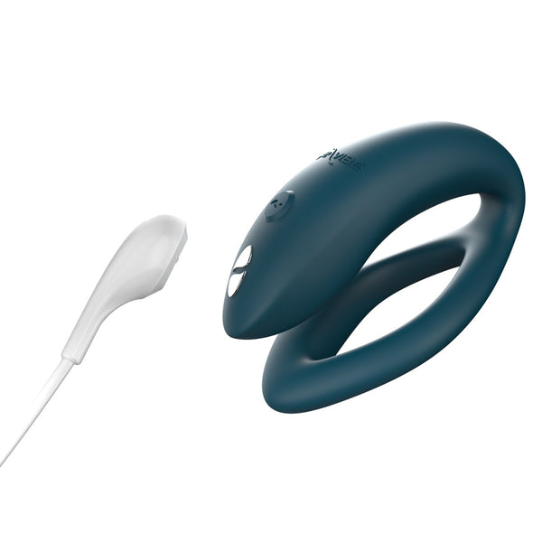 hands-free wearable c-shaped green We-Vibe sync O with the magnetic charging cord close to the toy, showing the toy is rechargeable