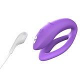hands-free wearable c-shaped lilac We-Vibe sync O with the magnetic charging cord close to the toy, showing the toy is rechargeable. 