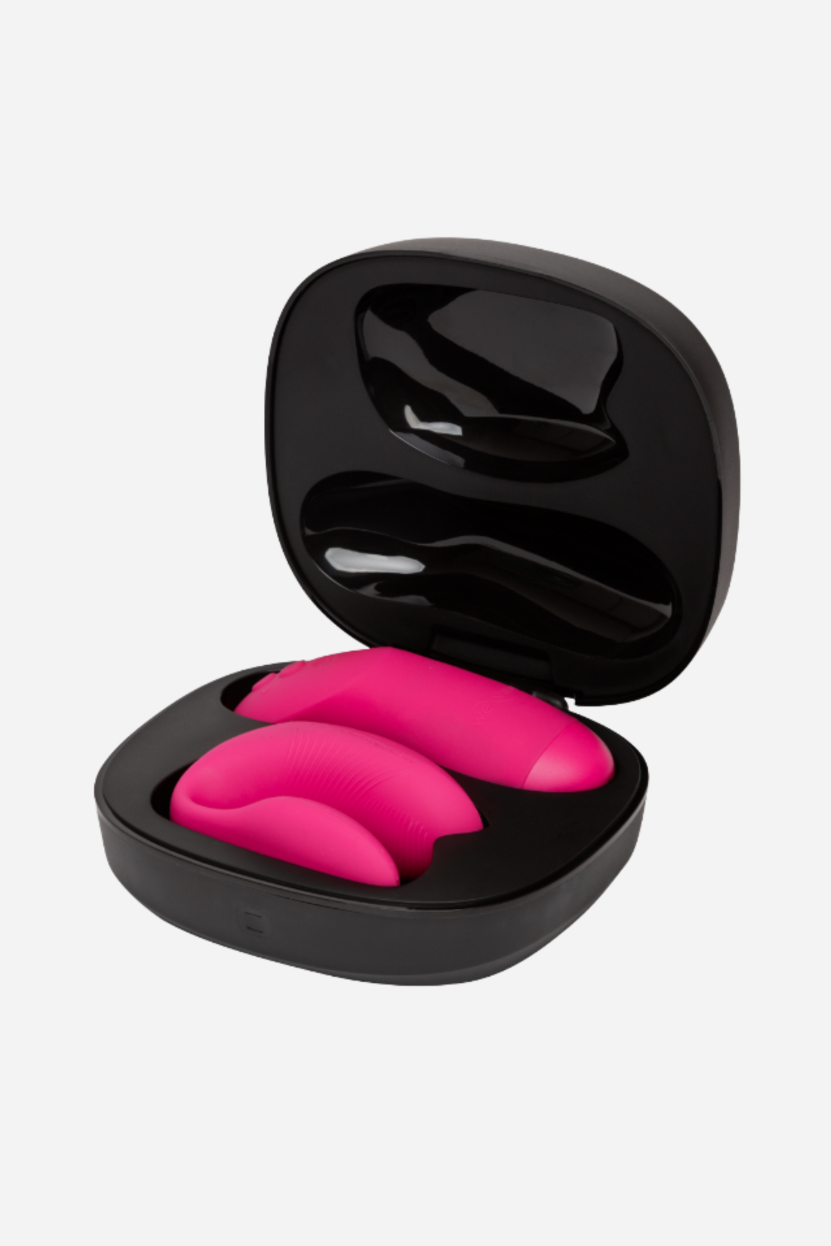 We-Vibe Chorus Pro in Hot Pink resting inside its open black charging case, showing how the vibe and remote store together