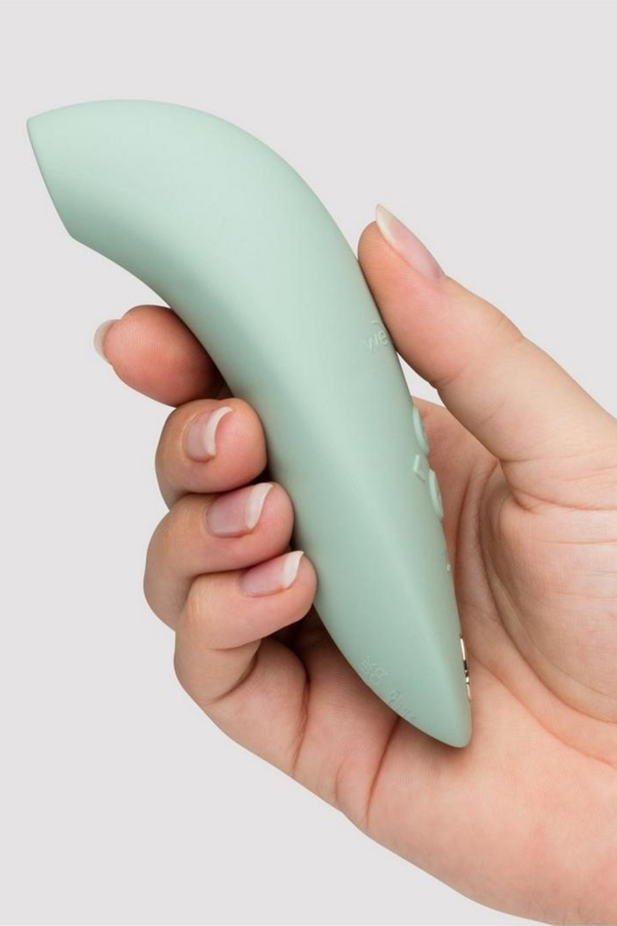 We-Vibe Melt 2 suction toy in Sage held in a hand, showing the curved shape and control buttons along the side on a grey background