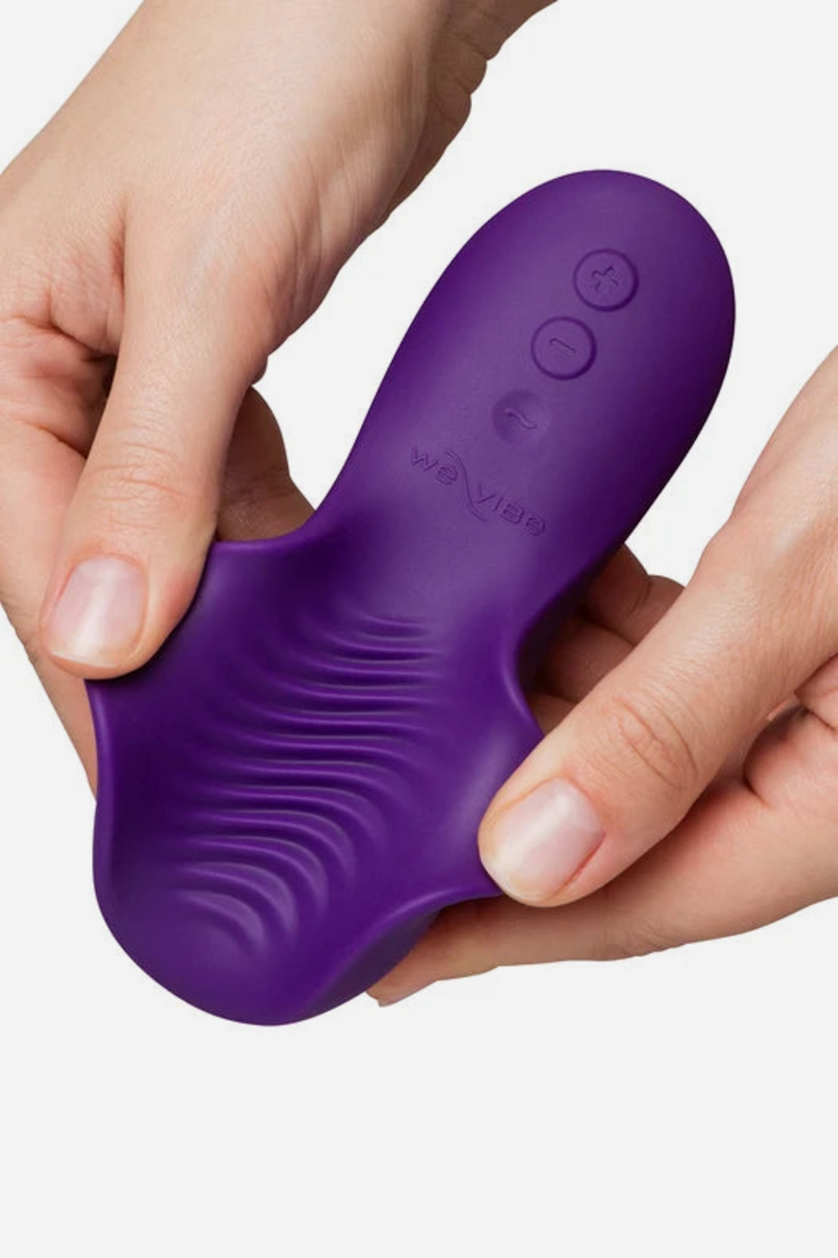 Two hands bending open the purple We-Vibe Shared Touch to reveal the soft wavy ridges across its underside and the control buttons on top