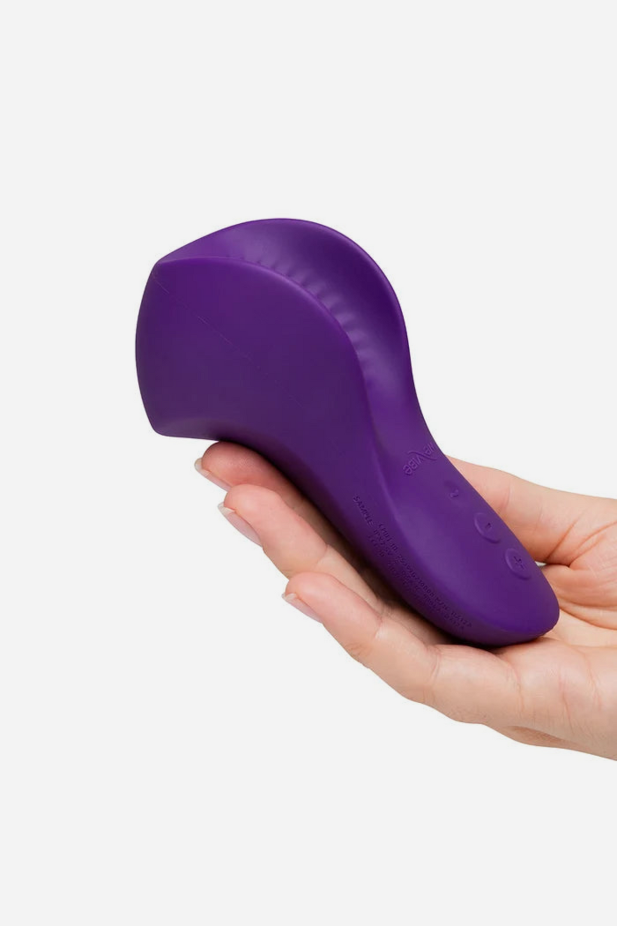 A hand holding the purple We-Vibe Shared Touch from below, showing its compact curved shape resting comfortably across the palm and fingers