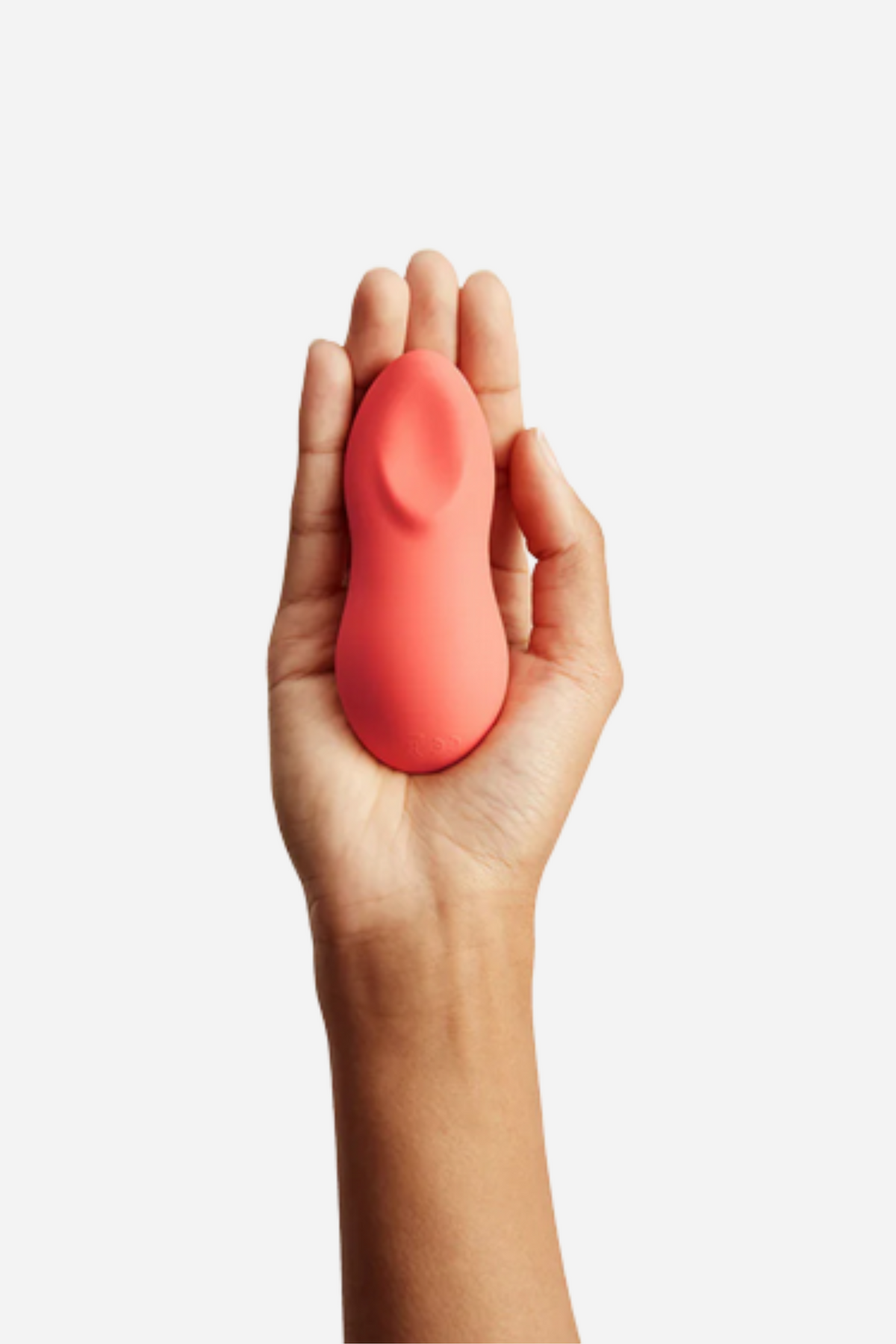 Hand holding the coral We-Vibe TouchX in an open palm to show its small, ergonomic size for easy external clitoral and body stimulation