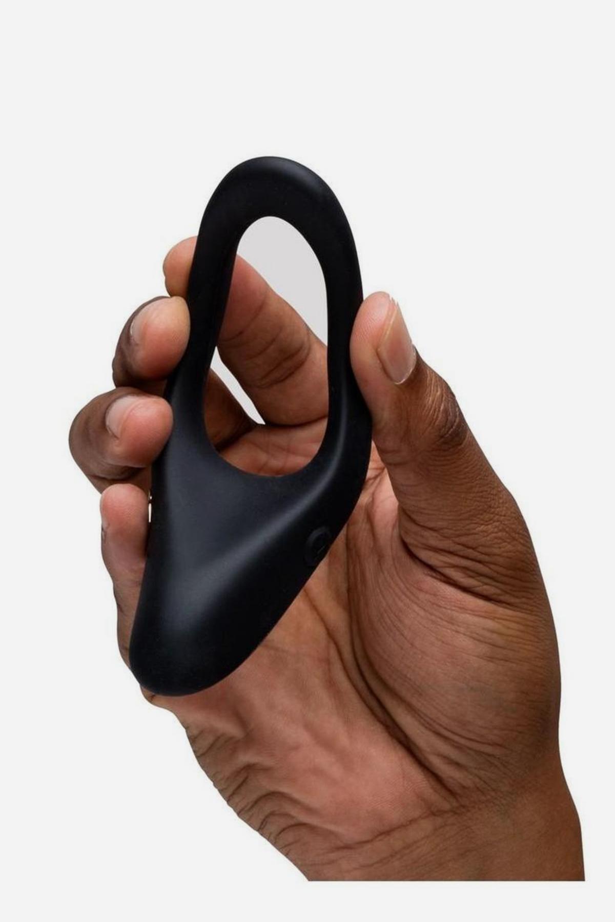 We-Vibe Verge 2 vibrating perineum cock ring in black held in one hand to show its size and flexible silicone, on a light grey background