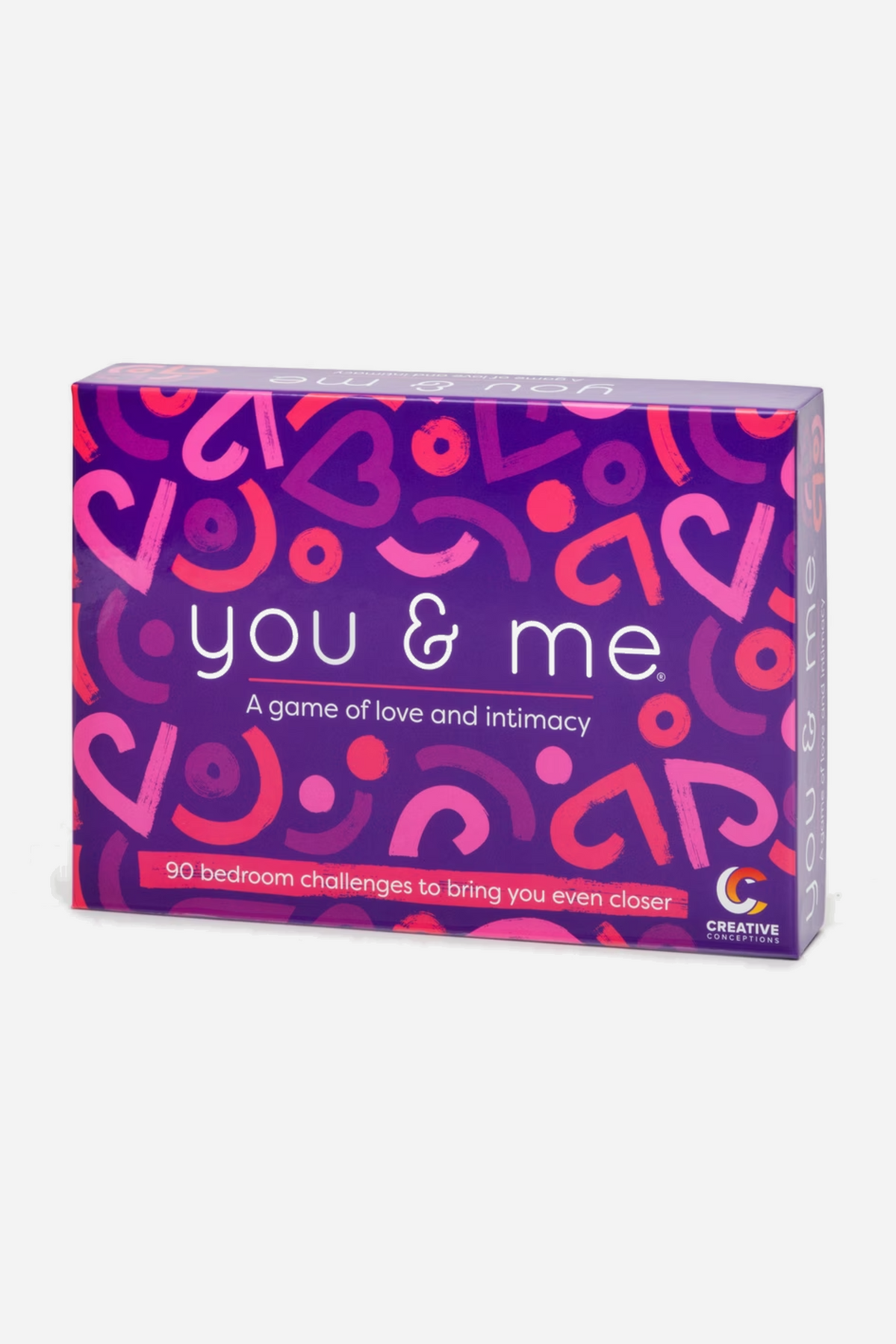 Front of the You and Me game box in purple and pink, reading a game of love and intimacy with 90 bedroom challenges to bring you closer.