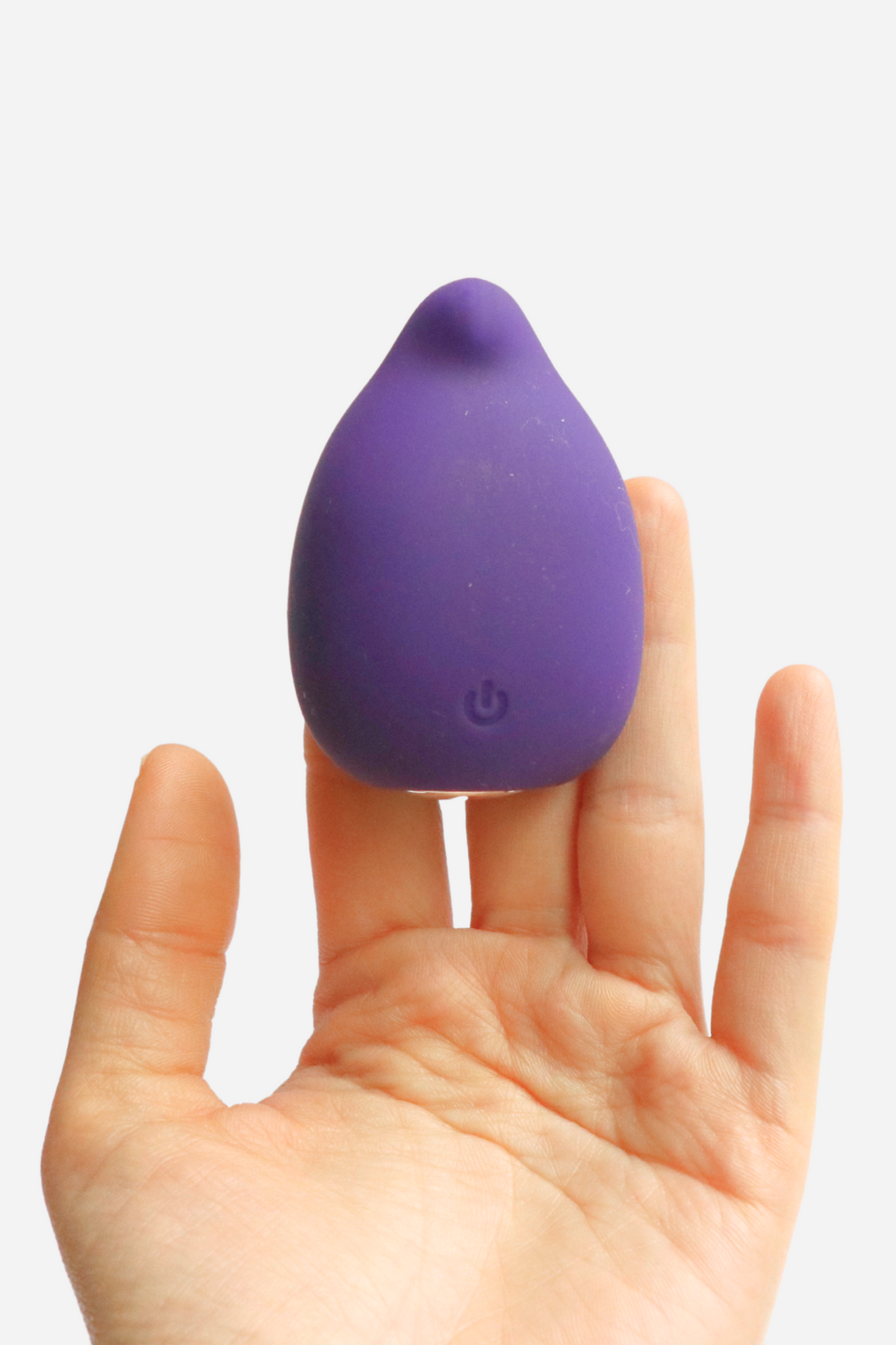 Hand holding the purple Yummy Finger Vibe upright on the fingertips, showing its small rounded shape and single power button