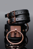 two inch thick vegan leather look cuffs stacked on top of one another. one shows off the bold rose gold hardware including a square plate with a 2in o-ring affixed to the front. the top one shows off the two strand buckles with elegant rose gold hardware.