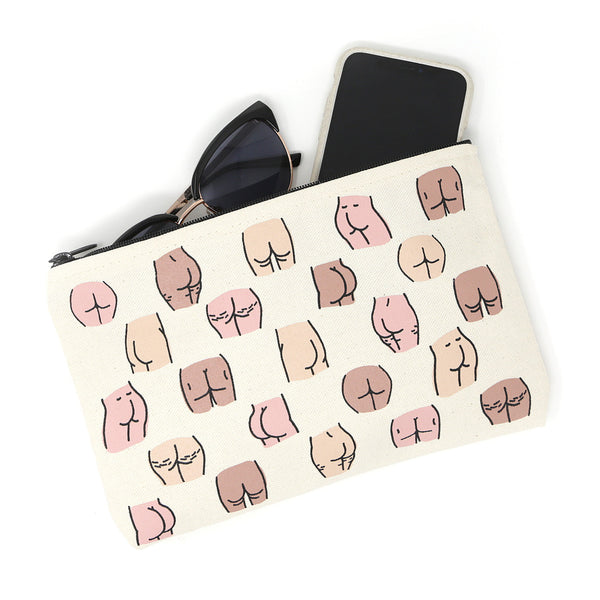 a neutral colored canvas pouch has screen printed repeating images of different butts- in several color skin tones.  At the top of the bag partial sunglasses and a phone are sticking out slightly.