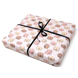 a gift showing off the wrapping paper with white background and butts outlines in different shapes, sizes, and colors. Tied with a black bow on top