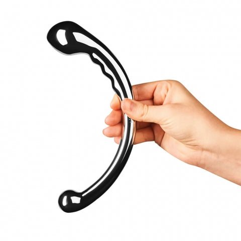 a white hand holds a stainless steel two-sided dildo, with one one having textured bumps and a larger tear dropped end, the other is a smaller 1" bulb for g-spot play