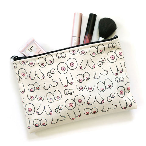 a neutral colored canvas pouch has screen printed repeating images of different sets of boobs. The boobs are outlines and most have pink areolas.  At the top of the bag makeup brushes are sticking out slightly.