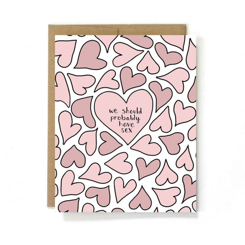A cute greeting card. Pink hearts surround a larger pink heart in the middle of the card. The text in the middle heart reads “we should probably have sex”  This card is made by Unblushing a Women-Owned small sex positive graphic designer.